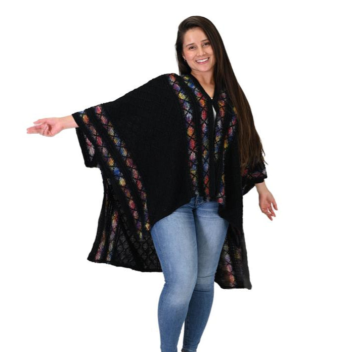 Woman wearing a black poncho with colorful patterns on a white background